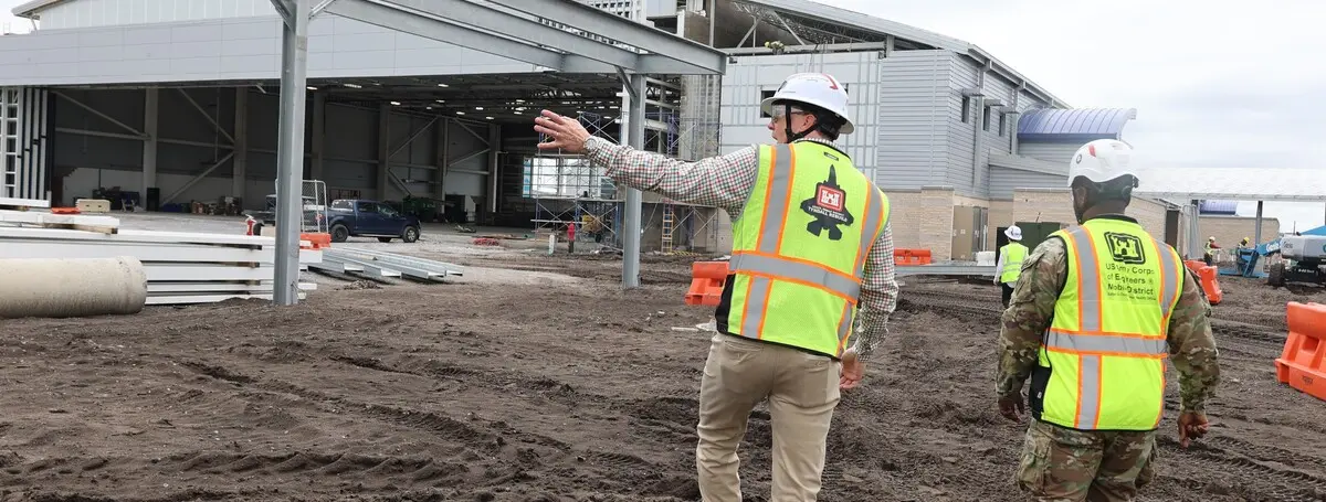 Uniformed USACE commander and civilian resident engineer touring an active aircraft hangar construction site